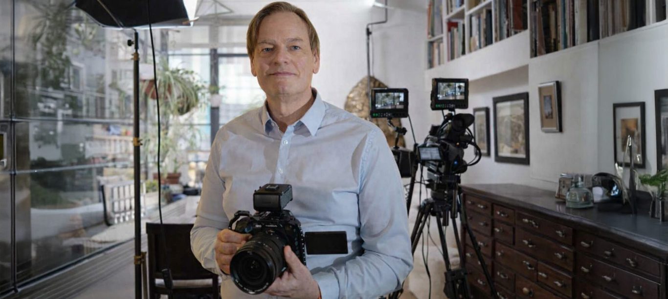 Olivier Dupont, vidéo LinkedIn pour les coachs, consultants et experts Homme tenant un appareil photo dans un studio avec des caméras en arrière-plan.